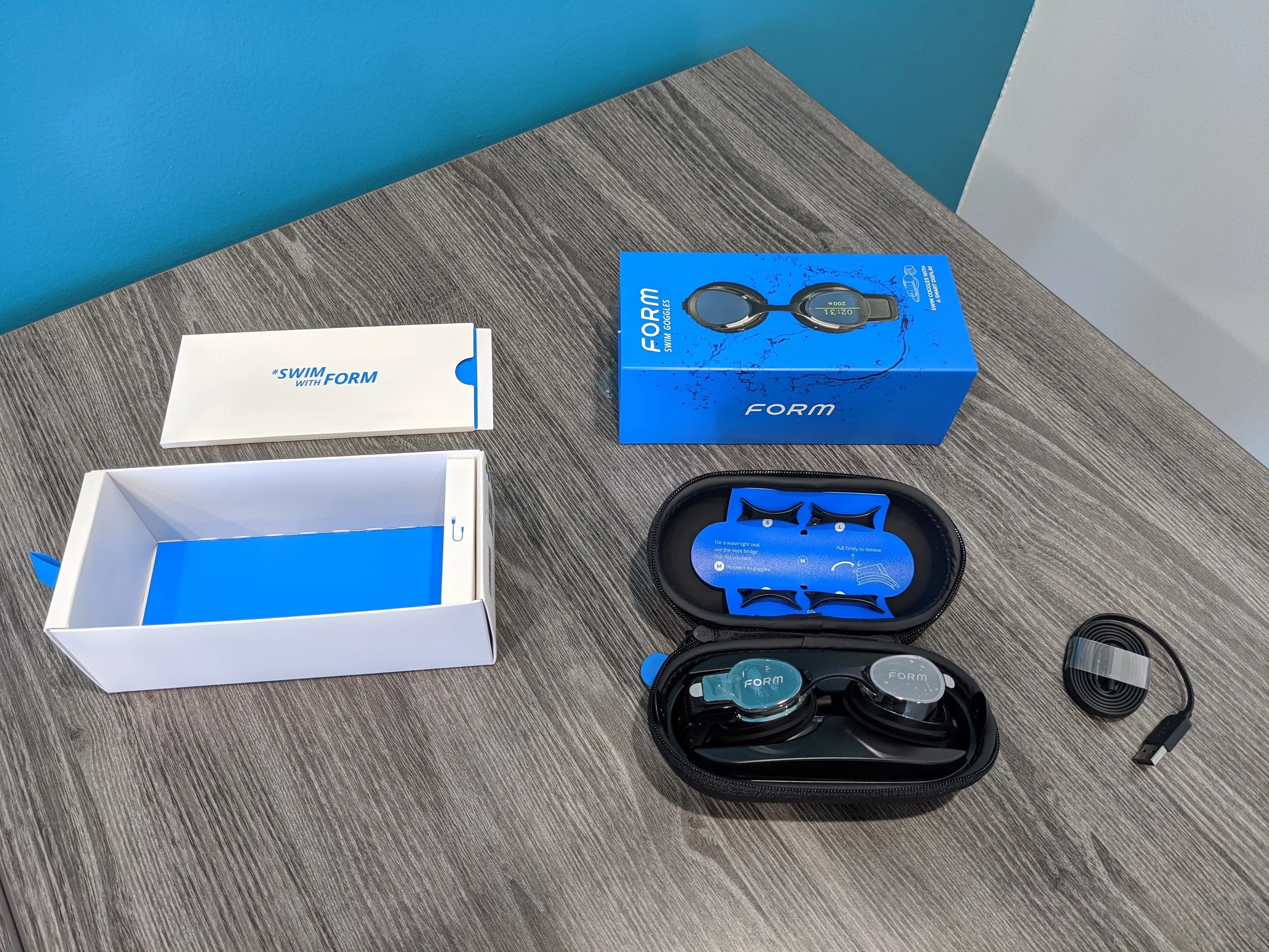 Wireless earbuds on a wooden table with packaging.