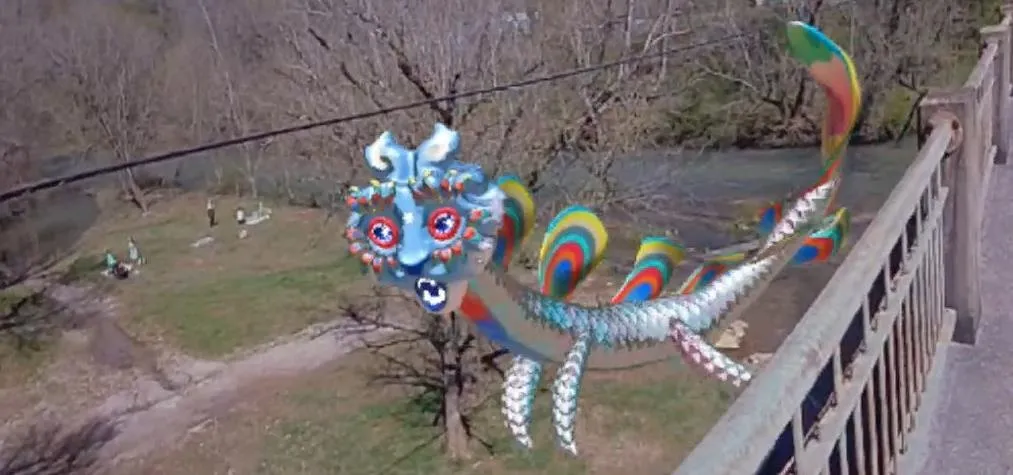Colorful dragon sculpture or installation near a riverbank.